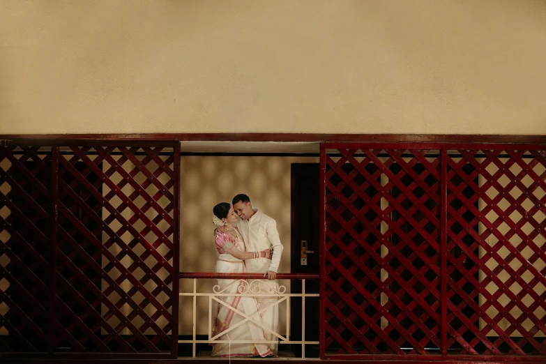 a couple standing on a balcony with red gates