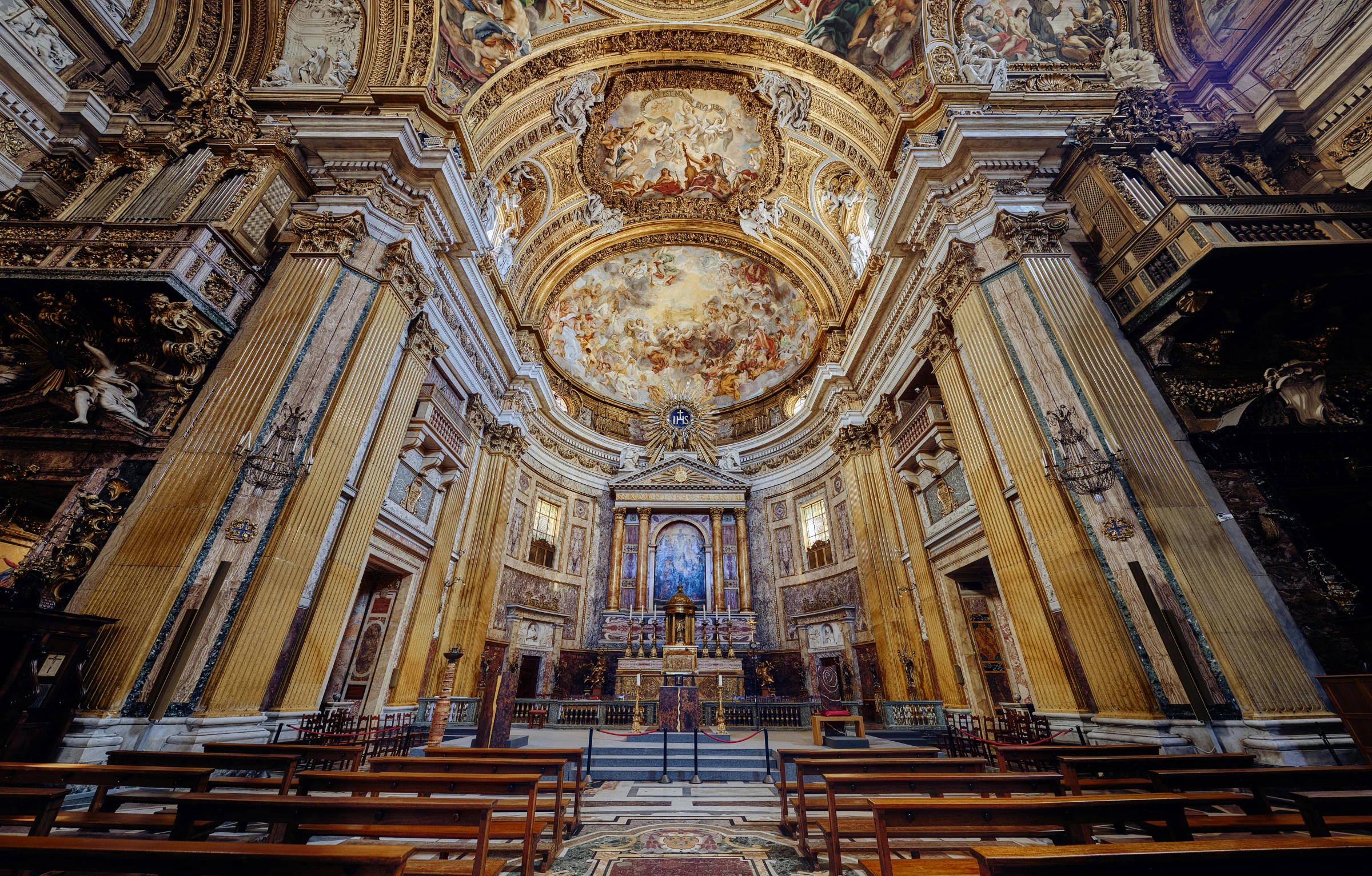 a church with an intricate painted ceiling and gold pew