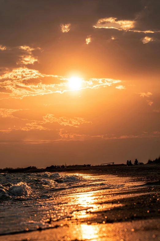 a sunset s with the ocean and people walking on the beach