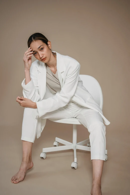 a woman in white pants and jacket sitting on a chair