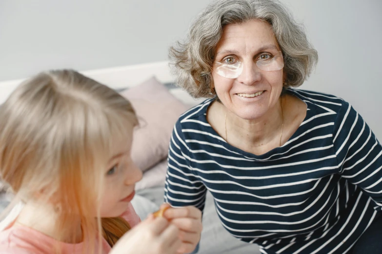 an older woman brushing her teeth beside a little girl