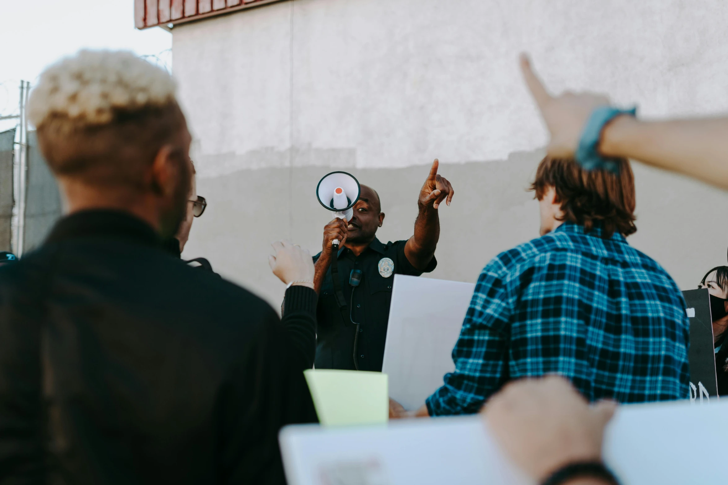 man raising his hand with his fist in front of another man in front of a building