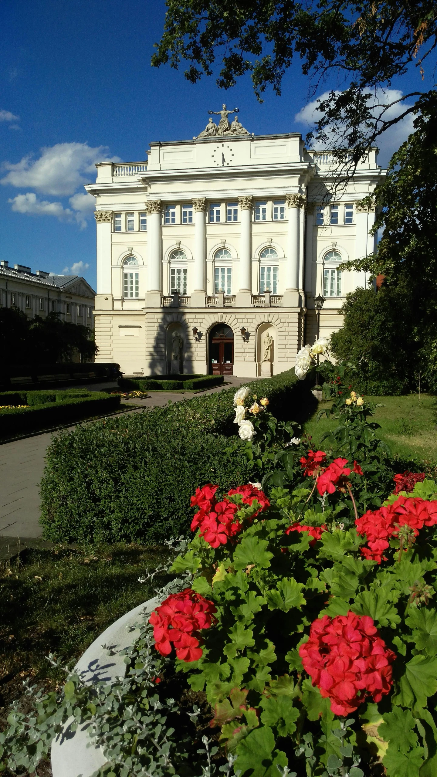 a big building with flowers by the road