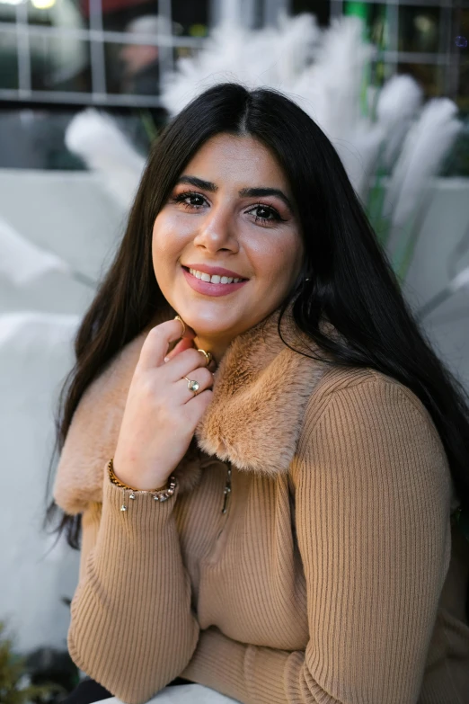 a woman with brown sweater and fur collar smiling