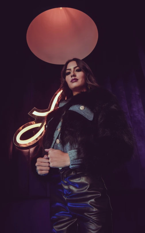 a woman is standing with her arms crossed in front of a lit neon sign