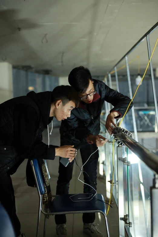 two boys standing by a railing with a chair