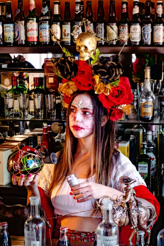 woman wearing a colorful costume at a bar with various bottles in the background