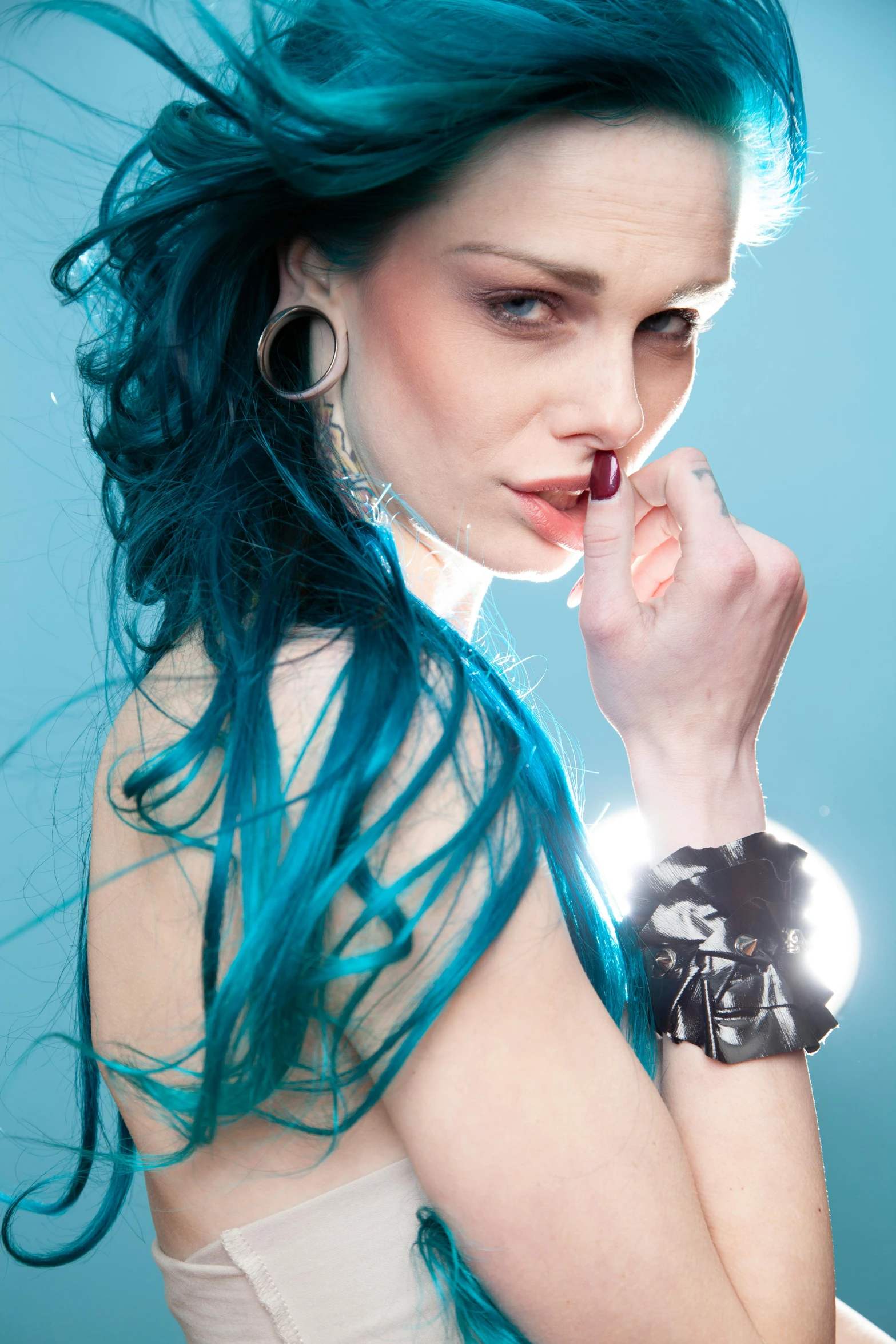 a pretty young lady with blue hair holding a cell phone to her ear