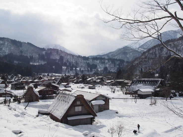 a snowy landscape shows houses, mountains and trees