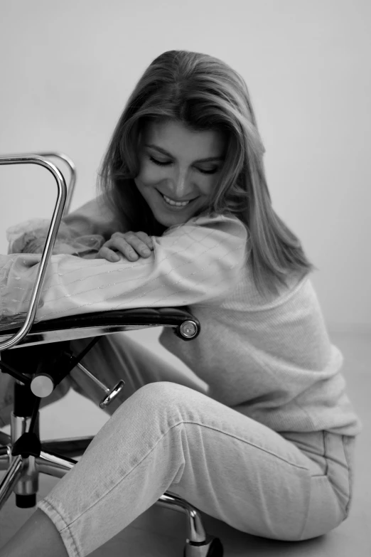 a black and white image of a woman sitting on the back of a chair