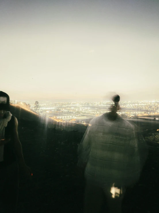 two people are standing in front of a window and looking over the city