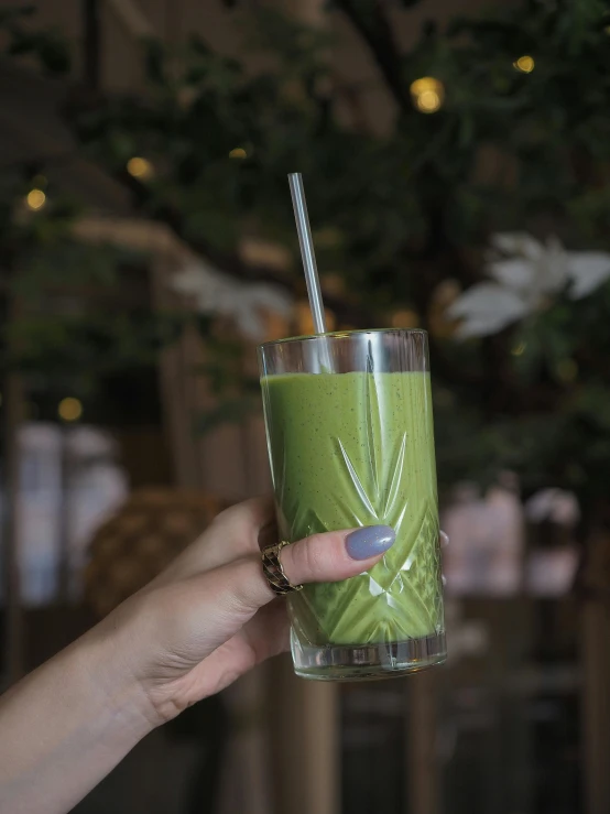 hand holding green beverage with a straw in it