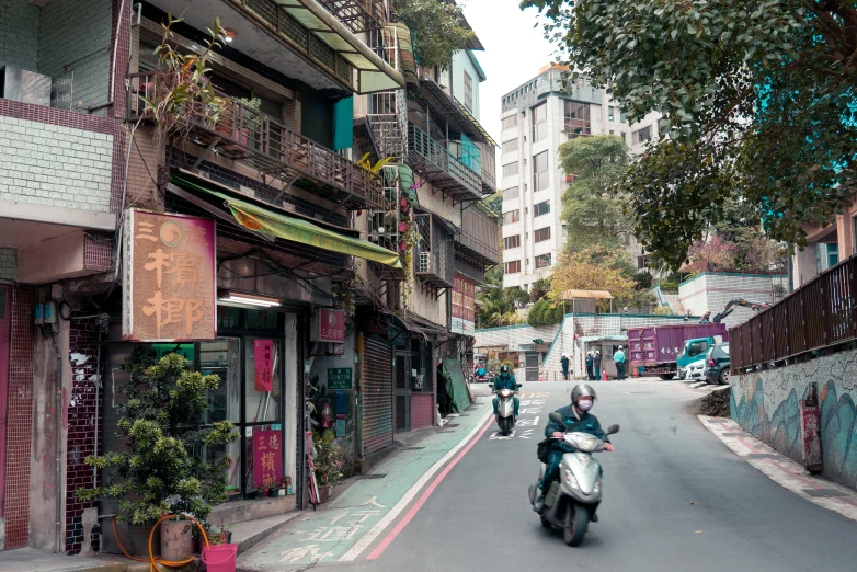 three people riding motorcycles down the middle of a narrow street