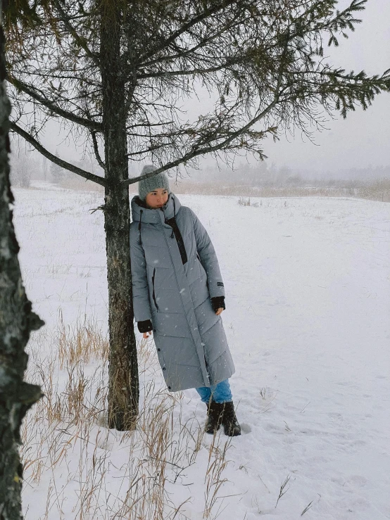 a woman in the snow, next to a tree