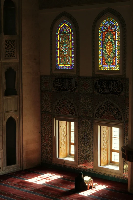 a person is sitting on the floor in front of stained glass windows