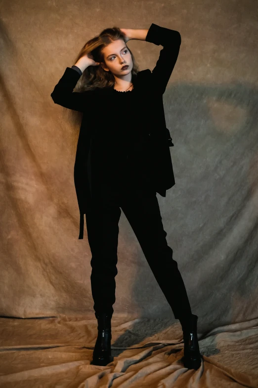 a woman standing against a grey backdrop wearing black