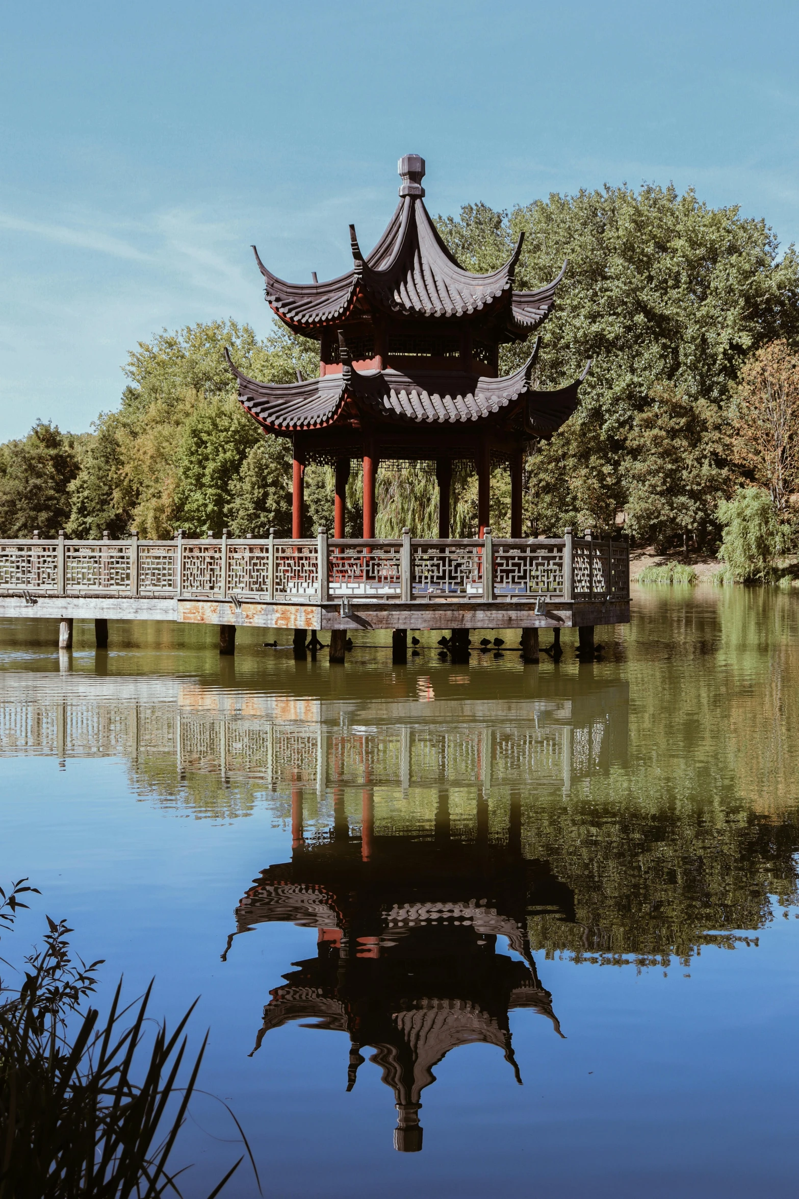 a pagoda is on the water near a bridge