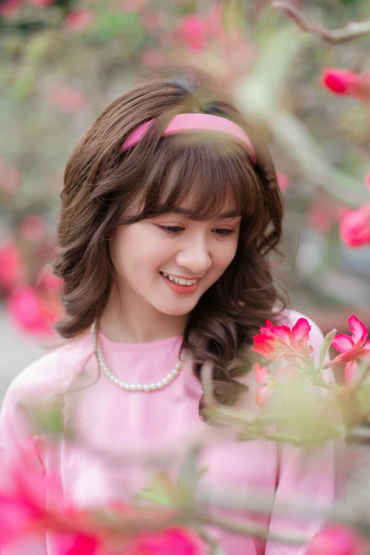 a girl in pink holding a flower smiles