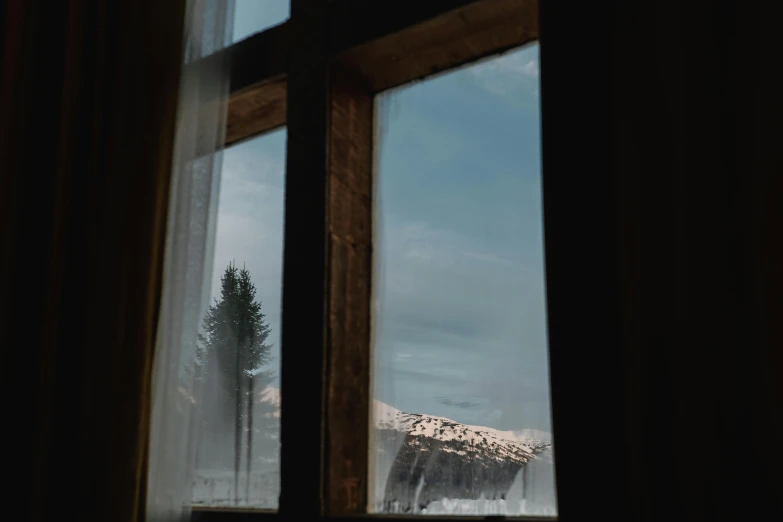 a view from outside of a window looking at snow covered mountains