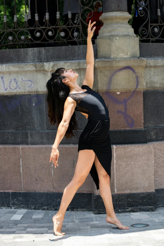 a woman wearing black dancing while holding her arms above her head