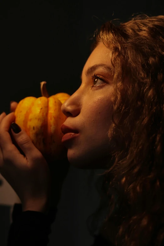 a woman holding an orange up to her face