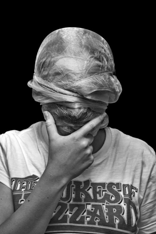 black and white pograph of woman covering face with cloth on head