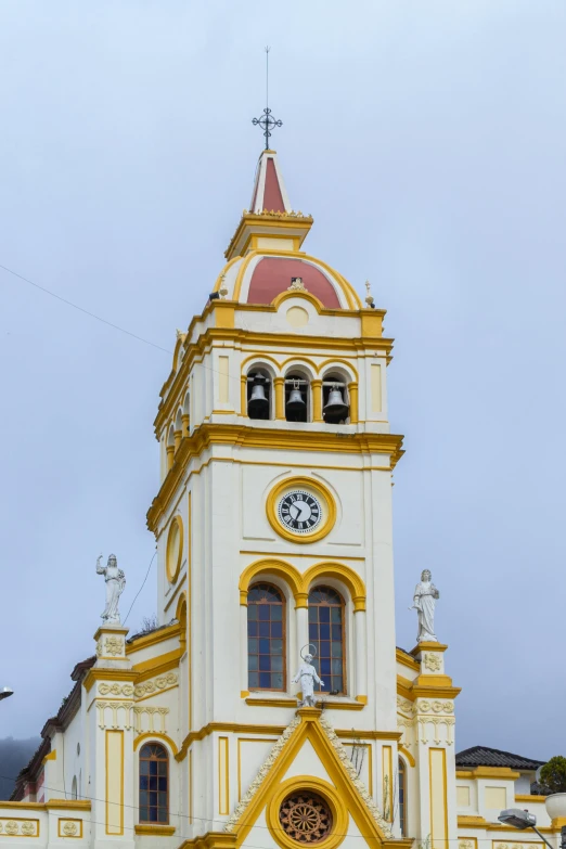 a white and yellow church has a clock