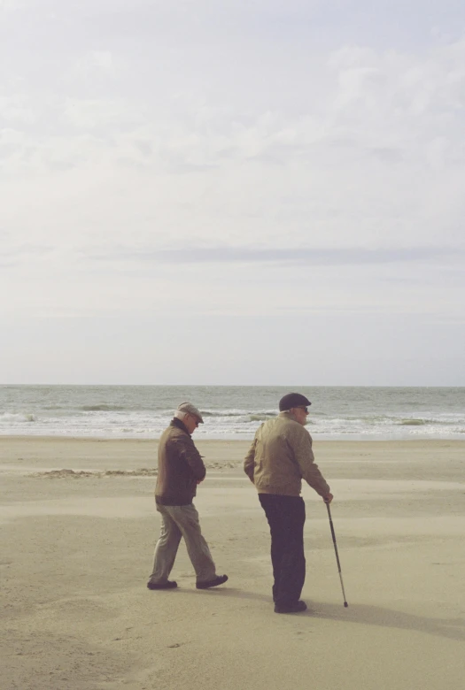 two men standing on a beach in the sand