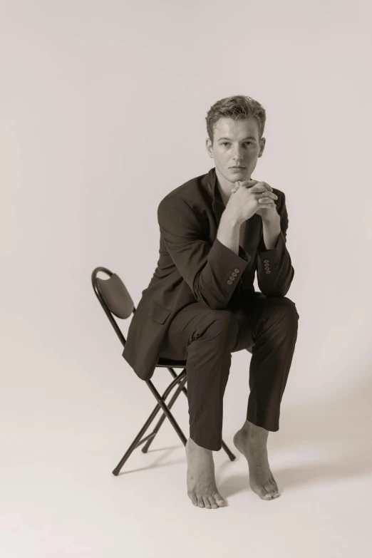 a man sitting on a folding chair with his hand resting on his chin