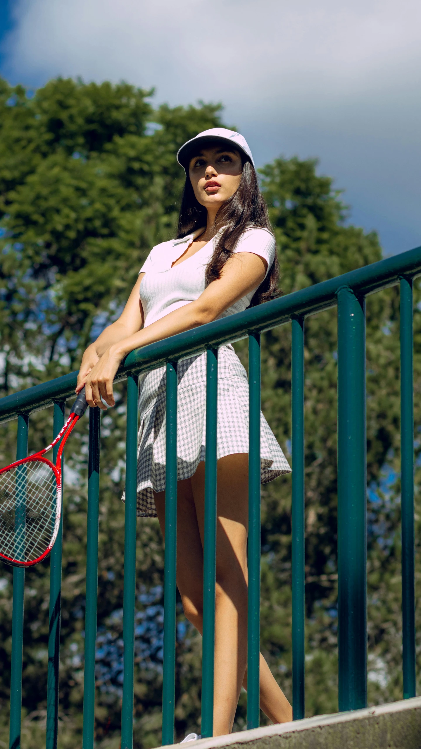a woman leaning on the railing with her racquet