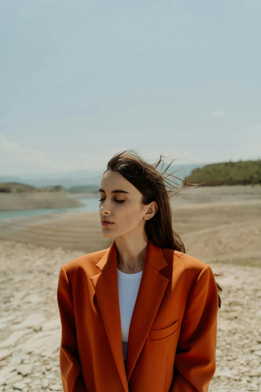 woman wearing an orange suit looks out to sea on beach