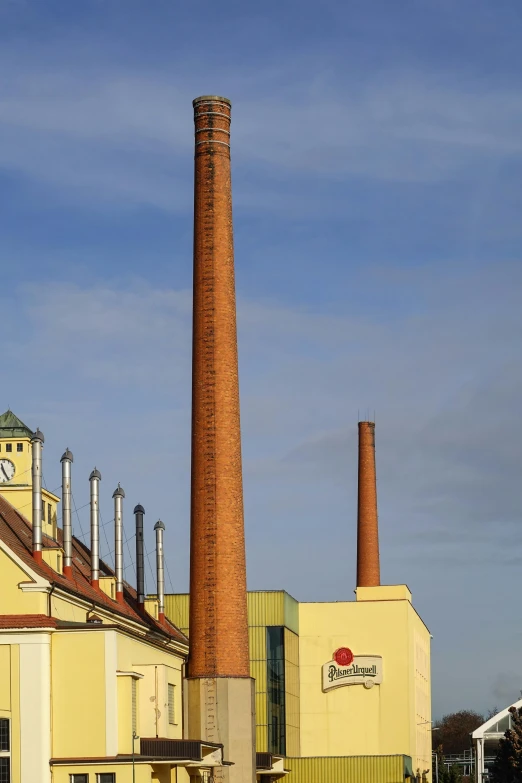 a brick factory with a tall smoke stack near a building