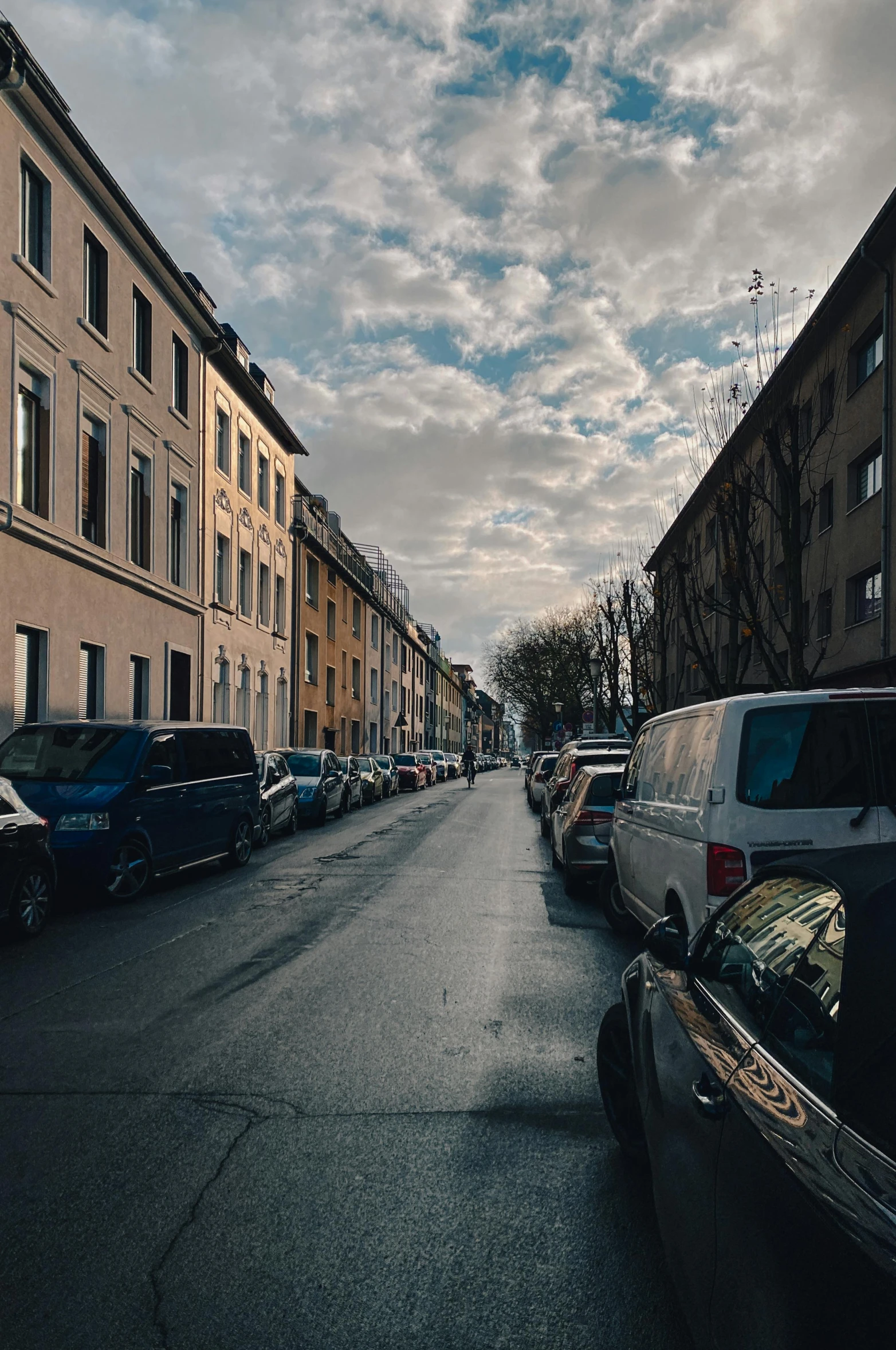 cars parked along the side of a street with a cloudy sky