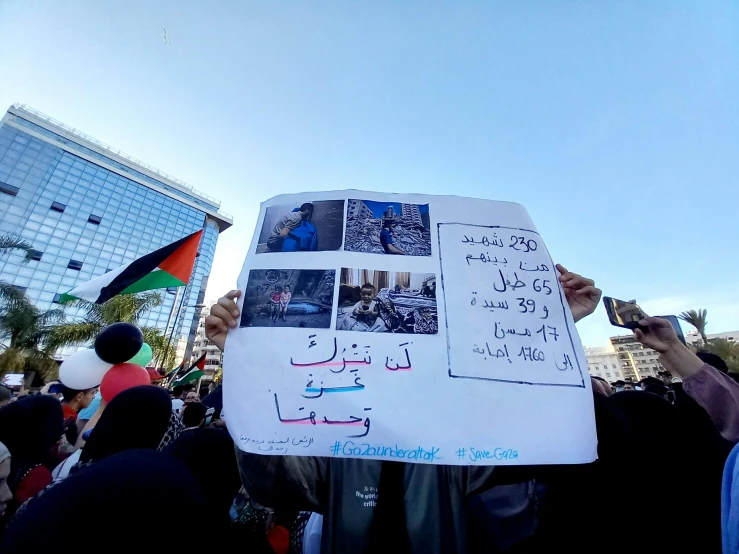 people protesting with large white sheet and hand written names of victims in arabic