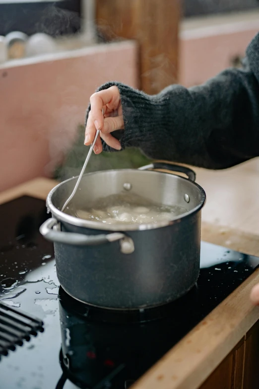 a woman cooking with a fork in the pot