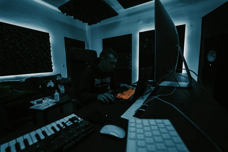 man sitting at computer desk with keyboard and monitor