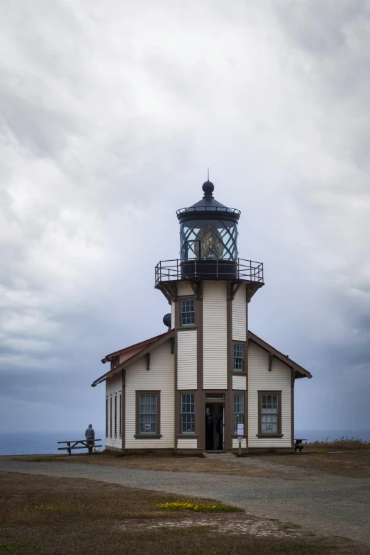 a lighthouse is standing alone on top of a hill