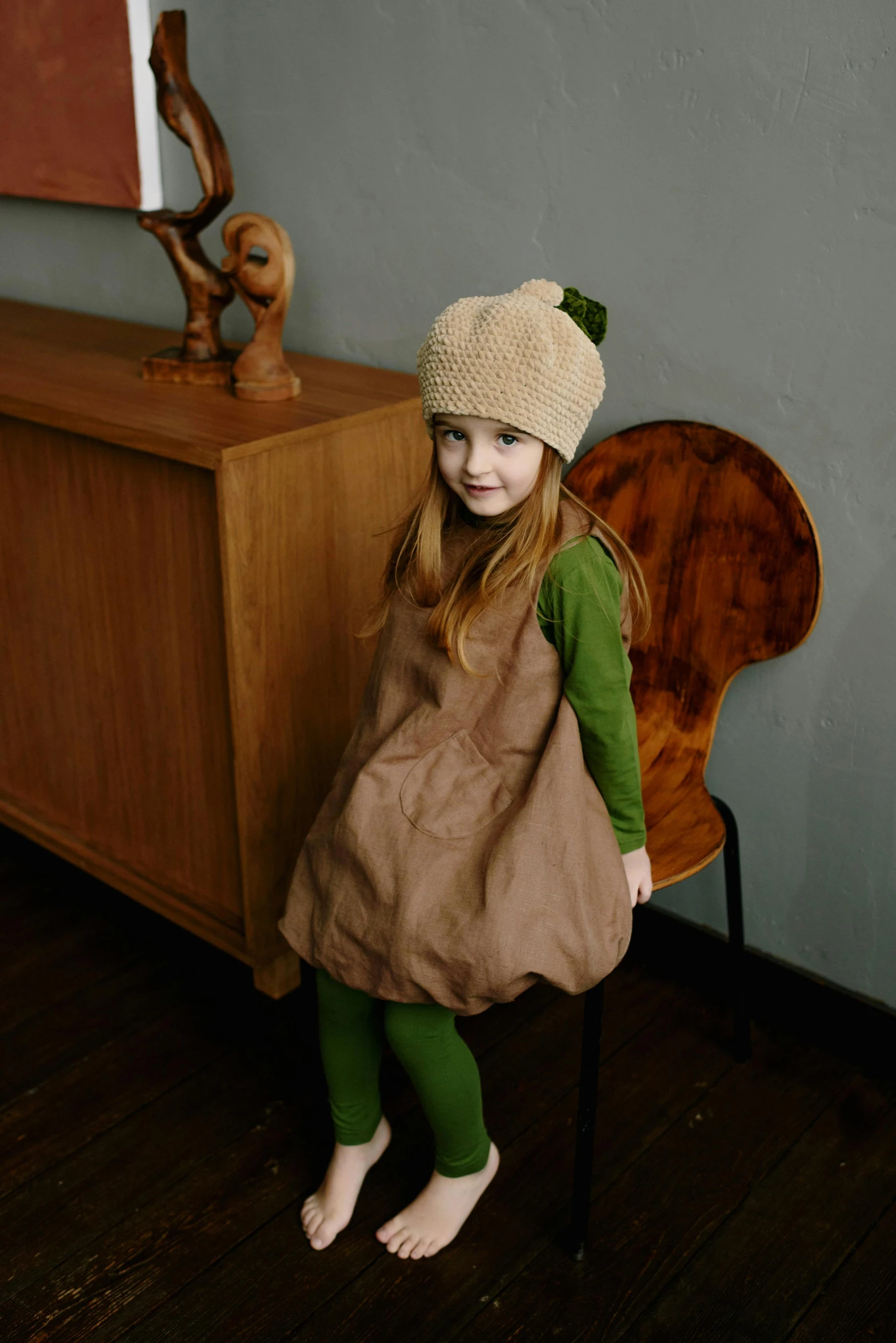 a little girl with a purse on the floor next to a dresser