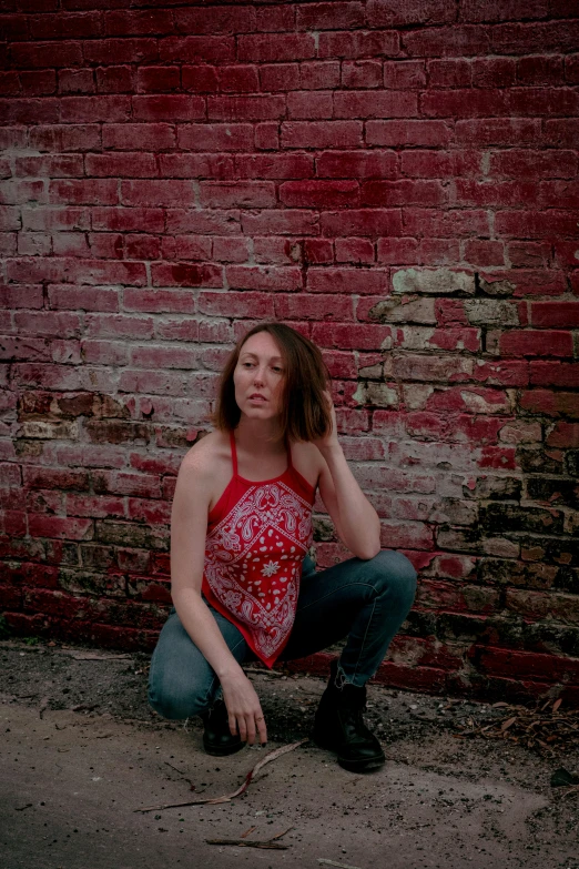 the woman squats near the brick wall