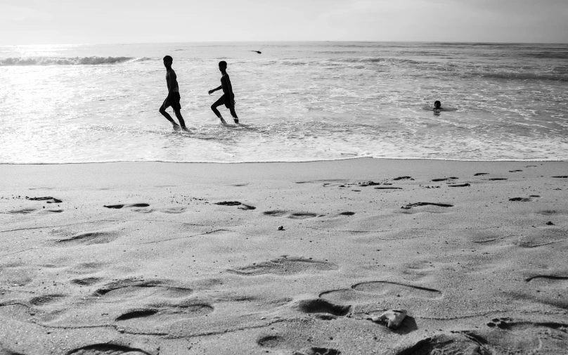 two people are walking out from the water at a beach