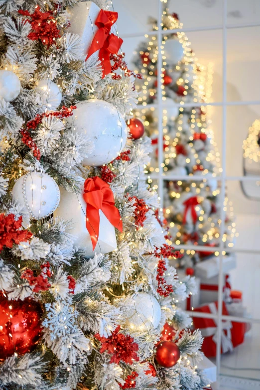 a white christmas tree decorated with red and white ornaments