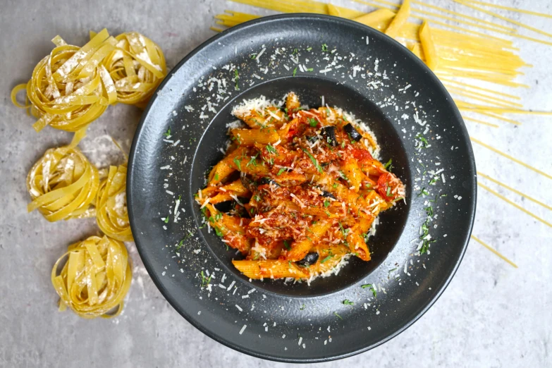 a black plate topped with pasta and sauce