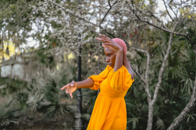 a woman wearing a yellow dress and a head scarf is throwing soing