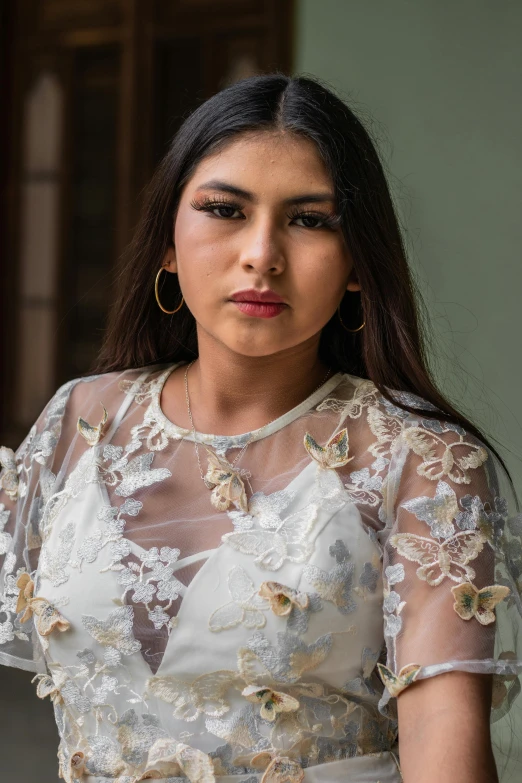 a woman wearing gold hoop earrings and a sheer dress