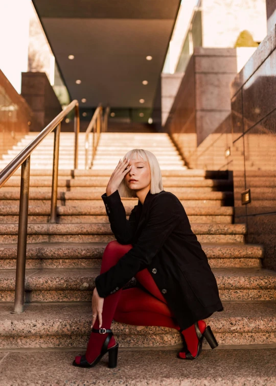 a woman sitting on the stairs with her hand over her head