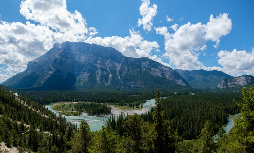 the mountains are filled with pine trees and clouds