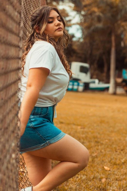 a young lady leans against a brick wall