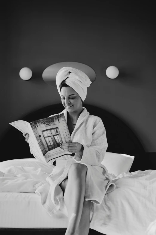 a woman is sitting on her bed with a towel over her head