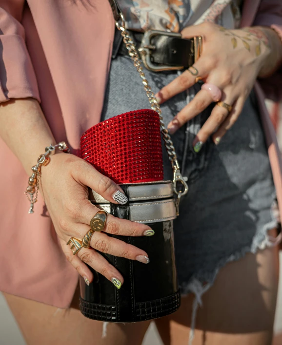 woman with tattoos, showing her nails and manicures holding a purse