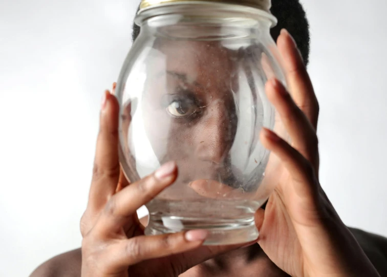 a woman holding a large jar over her face